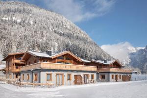 dom w śniegu z górą w tle w obiekcie Alpin Residenzen Buchensteinwand St. Ulrich by Alpina-Holiday w mieście St. Ulrich am Pillersee