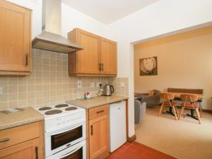 a kitchen with a stove top oven next to a living room at Cinder Cottage in Worcester