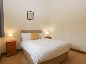 una camera da letto con un letto con lenzuola bianche e due lampade di Cinder Cottage a Worcester