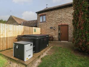 a backyard with a barbecue grill and a house at Larch Bed Cottage in Worcester