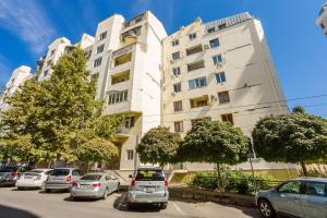 a tall white building with cars parked in front of it at Rustaveli Three Bedroom Apartment with Amazing views in Tbilisi City
