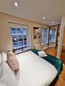 ロンドンにあるArtillery Lane Apartmentsの窓2つが備わる客室で、白い大型ベッド1台が付いています。