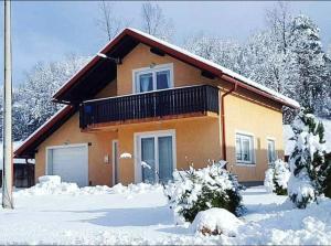 a house with a balcony in the snow at Holiday home Zulejka in Ogulin