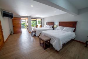 1 dormitorio con 2 camas y TV de pantalla plana en Flower’s Paradise Monteverde, en Monteverde