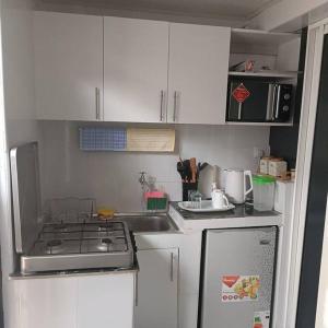 a small kitchen with a stove and white cabinets at Sharz place in Nairobi