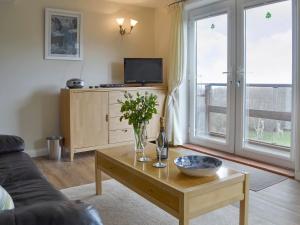 a living room with a coffee table and a tv at The Cottage in Fairlight