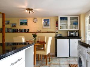 a kitchen with a table and white appliances at The Cottage in Fairlight