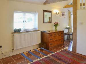 a room with a bed and a dresser and a window at The Stables in Elmstone