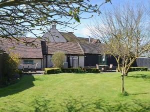 una casa con un patio con bancos y un árbol en The Stables, en Elmstone