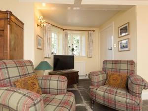 a living room with two chairs and a flat screen tv at Big Barns Cottage in Backies