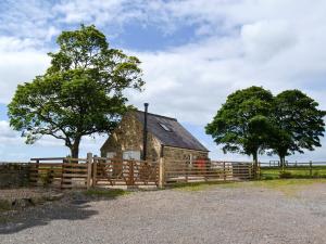 um velho celeiro com uma cerca de madeira e árvores em Sycamore Cottage em Consett