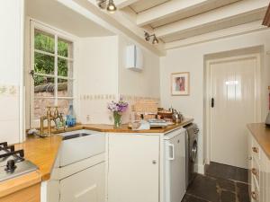 a kitchen with white cabinets and a sink and a window at Big Barns Cottage in Backies