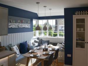 a dining room with a table and chairs and windows at Beach Haven in Sheringham