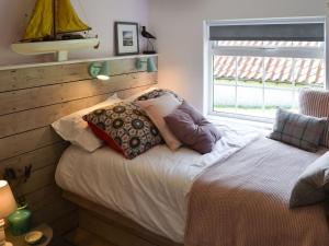 a bed with pillows on it in a room with a window at Beach Haven in Sheringham