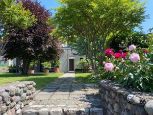 a garden with pink flowers and a stone wall at Holiday home Punta D'Oro with garden, parking place and lake access at 300 m in Iseo