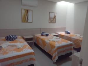 a room with two beds with orange and white sheets at FLATS MANOEL TAVARES in Garanhuns