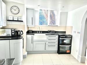 a kitchen with white cabinets and a clock on the wall at Cosy One Bedroom Apartment in Trowbridge