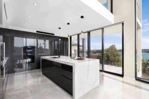 a kitchen with black and white appliances and large windows at SYD Luxury cheerful water view holiday house in Sydney