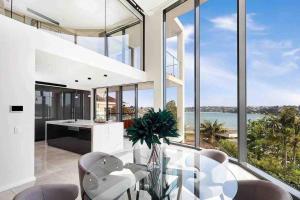 a dining room with a glass table and chairs at SYD Luxury cheerful water view holiday house in Sydney