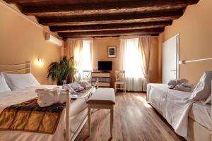 a bedroom with two beds and a desk with a television at Ca' Riza in Venice