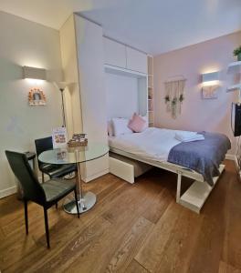 Dormitorio pequeño con cama y mesa de cristal en London City Apartments, en Londres