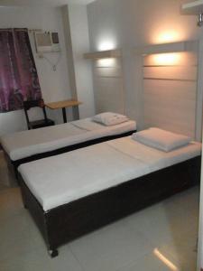 two twin beds in a room with a chair at D' Loft Inn CDO in Cagayan de Oro