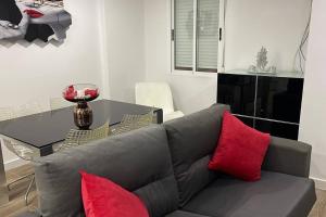 salon z szarą kanapą i czerwonymi poduszkami w obiekcie Moderno apartamento en Elche w mieście Elche