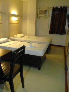 a bedroom with two beds and a table and a table and a chair at D' Loft Inn CDO in Cagayan de Oro