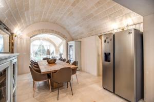 a kitchen and dining room with a table and a refrigerator at Trullo Rosa del Sud-Benessere SPA in Ceglie Messapica