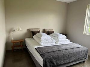 1 dormitorio con 1 cama con sábanas y almohadas blancas en Óspaksstaðir- New Renovated Farm in Hrútafjörður, en Staður