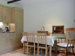 uma cozinha com uma mesa com cadeiras, uma mesa e um balcão em Llwyn Onn em Newchurch