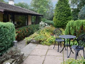 a patio with two chairs and a table in a garden at Llwyn Onn in Newchurch