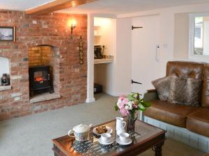 a living room with a couch and a brick fireplace at The Brambles in Horning