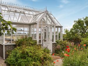 a white greenhouse in a garden with flowers at Church View - Ukc5700 in Castletown