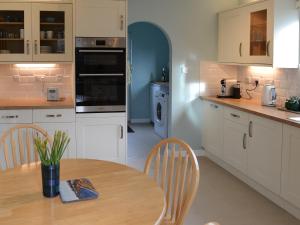 a kitchen with white cabinets and a table with chairs at Killearn Cottage in Portmahomack