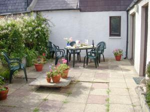 a patio with a table and chairs and potted plants at Killearn Cottage in Portmahomack