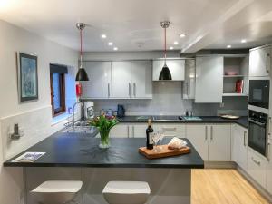 cocina con armarios blancos y encimera negra en Windmill Barn en Herstmonceux