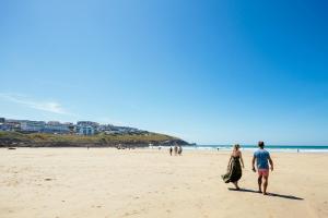 a man and a woman walking on the beach at Fistral Beach Hotel and Spa - Adults Only in Newquay