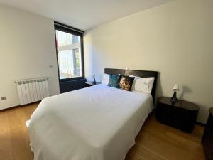 een slaapkamer met een groot wit bed en een raam bij Gerês Distinto - Glória in Geres