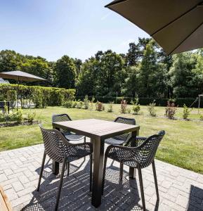 una mesa con sillas y una sombrilla en el patio en Luxe woodlodge in een prachtige en bosrijke omgeving, en Bornerbroek