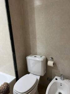 y baño con aseo blanco y lavamanos. en Callao Suites en Rosario