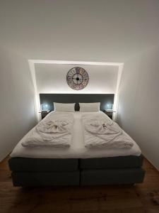 sypialnia z dużym łóżkiem z zegarem na ścianie w obiekcie Das Fischer Boardinghouse KF w mieście Kaufbeuren