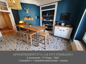 ein Esszimmer mit einem Tisch und einer blauen Wand in der Unterkunft La Maison des Familles 10 appartements in Le Mont-Dore