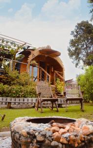 two chairs and a fire pit in front of a cabin at Glamping Cabañas Sharmont in Guarne