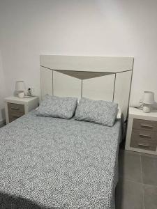 una camera con un letto con due comodini e due lampade di Confortable adosado en Elche a Elche