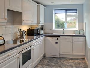 a kitchen with white cabinets and a sink and a window at Whitegate View in South Chard