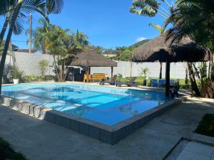 uma piscina num resort com palmeiras em Linda casa na Barra do Sahy 1 (Litoral Norte SP) em São Sebastião