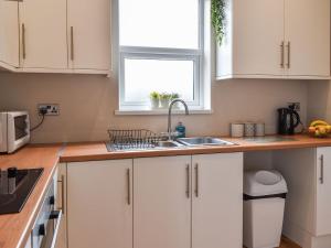 a kitchen with white cabinets and a sink and a window at Seion Villa in Blaenau-Ffestiniog