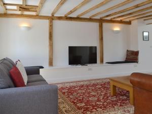 a living room with a couch and a flat screen tv at The Hop Cottage in Ashperton