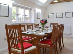 a dining room with a table with chairs and flowers at The Hop Cottage in Ashperton